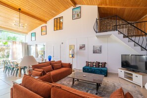 A spacious living area with a sofa set, a coffee table, a TV, and a staircase.