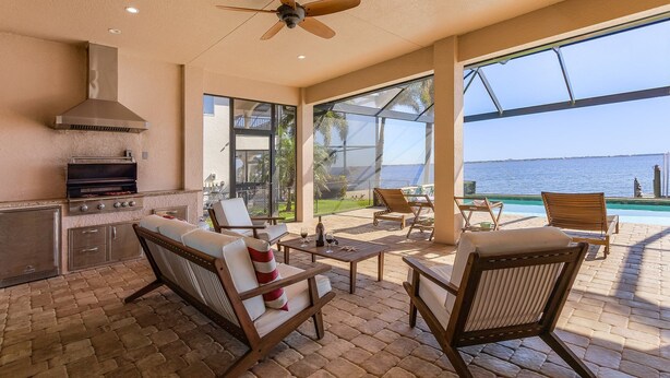Eine Terrasse im Freien mit Grill, Sitzgelegenheiten und Meerblick.