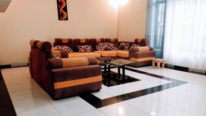 A living room with a sofa set, a coffee table, and a small table. - KIGALI FANTASTIC HOME AND BOUTIQUE HOTEL (Kigali)