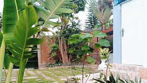 A garden with various plants, a brick wall, and a white door. - KIGALI FANTASTIC HOME AND BOUTIQUE HOTEL (Kigali)