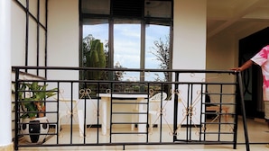 A balcony with a black metal railing, potted plants, and a view of the sky through the windows. - KIGALI FANTASTIC HOME AND BOUTIQUE HOTEL (Kigali)