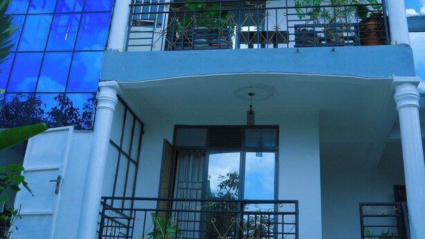 A multi-story building with balconies, large windows, and a blue facade. - KIGALI FANTASTIC HOME AND BOUTIQUE HOTEL (Kigali)