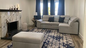 Ein Wohnzimmer mit Kamin, einer Sofagarnitur und einem gemusterten Teppich.