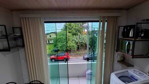 A small, clean room with a tiled floor, a washing machine, a dining table with chairs, and a view through a glass door to the outside. - Furnished loft close to In the center with private garage. (Jardim Iririú Joinville)