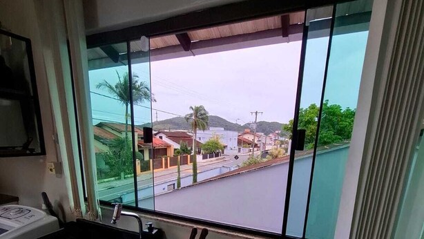 A kitchen with a large window, a sink, and a stove. - Furnished loft close to In the center with private garage. (Jardim Iririú Joinville)