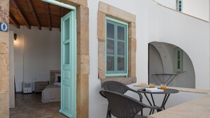 A room with a bed, a small table with chairs, and a window with a view.