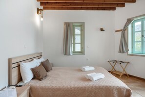 A bedroom with a bed, a wooden headboard, a window with curtains, a wall-mounted light, and a small drying rack. - Room 'Double  Sea View  No 5' with Sea View, Wi-Fi and Air Conditioning (Patmos)