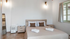 A bedroom with a bed, bedside tables, a heater, and a window.