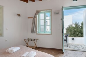 A bedroom with a bed, a drying rack, a window with curtains, and an open door leading to an outdoor area. - Room 'Double  Sea View  No 5' with Sea View, Wi-Fi and Air Conditioning (Patmos)