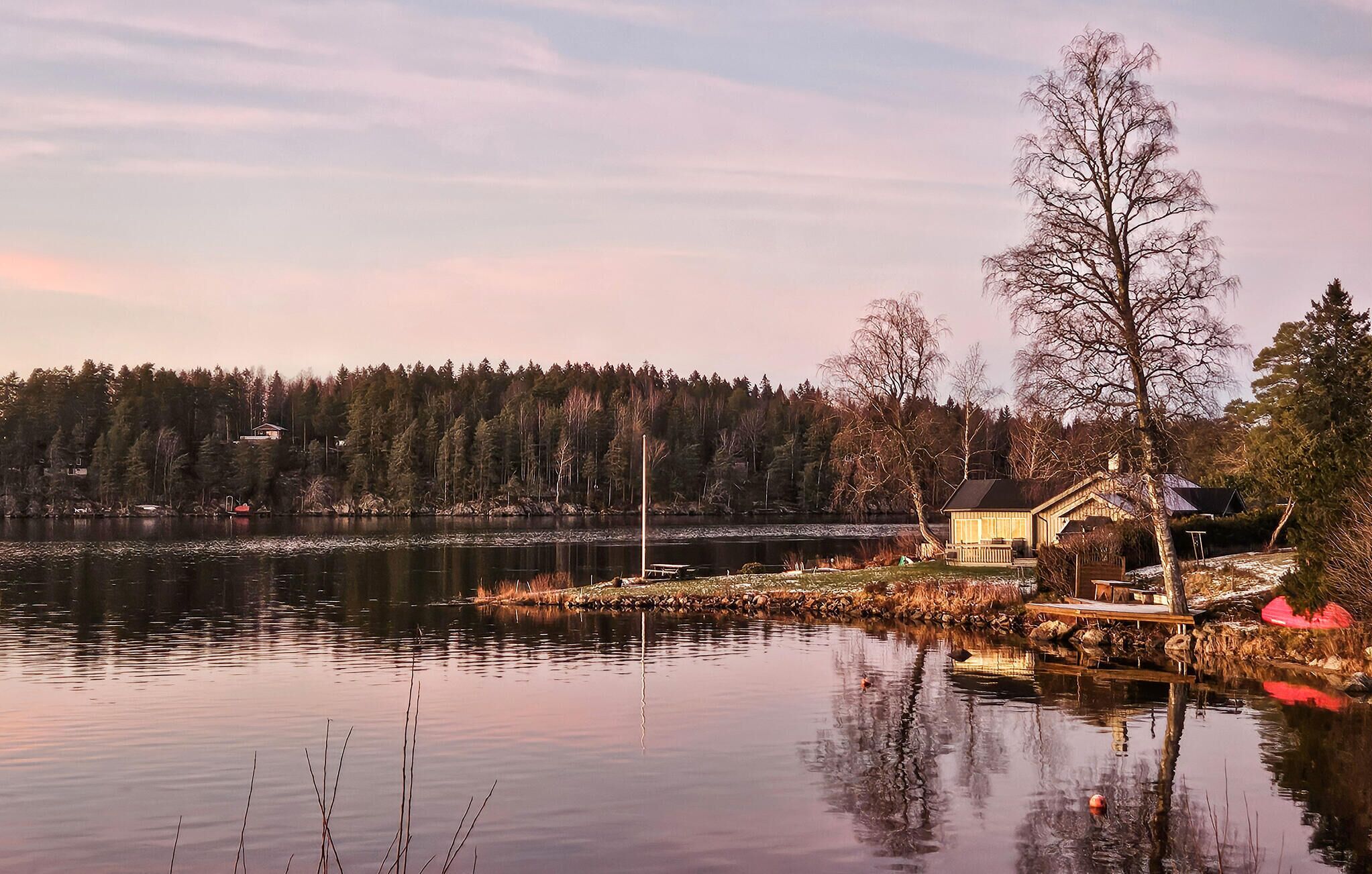 A lakeside cabin with a dock, surrounded by trees and a forest.