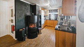 Eine kleine Küche mit Holzofen, Holzausstattung und Spüle aus Edelstahl.