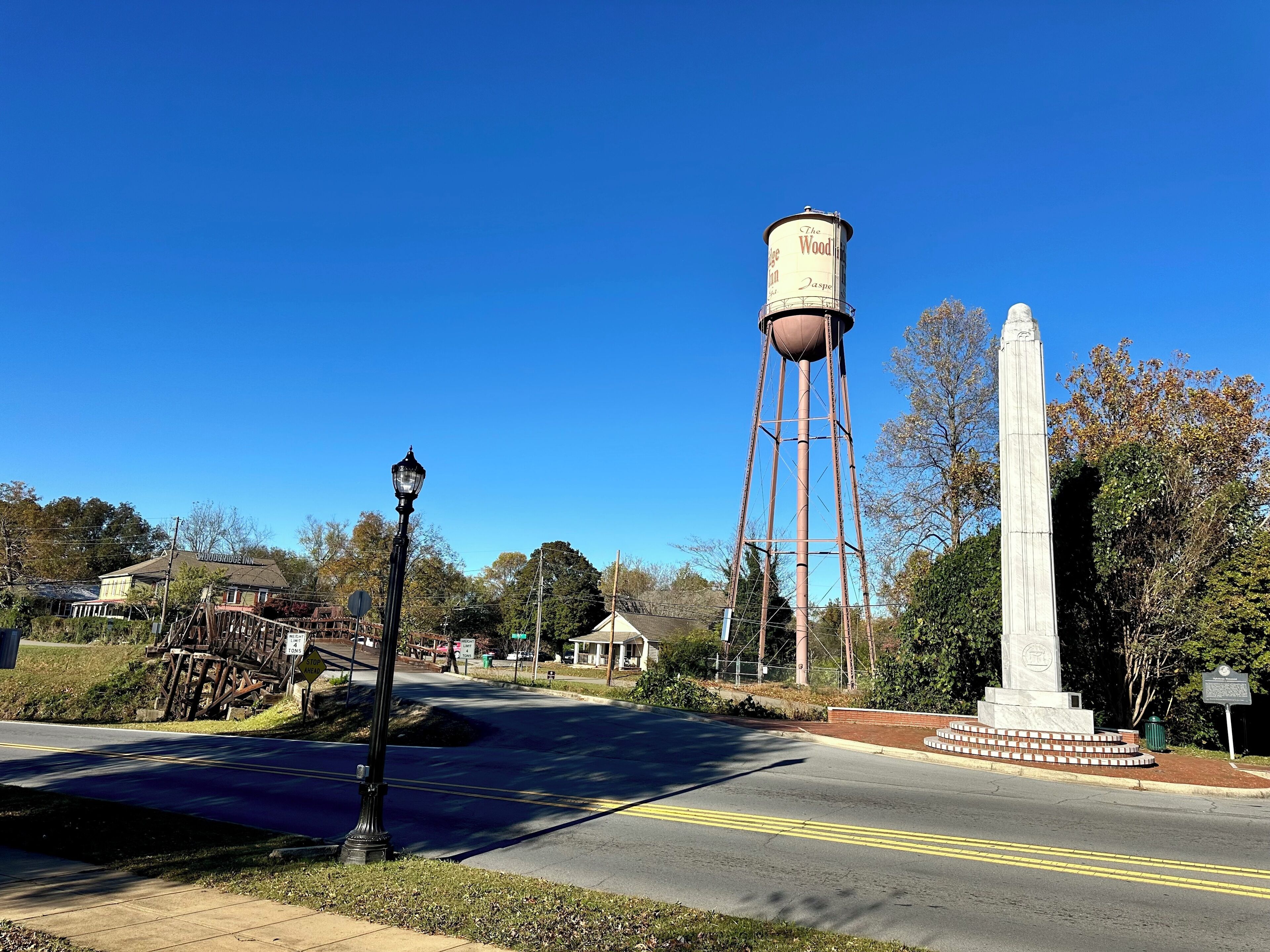 A water tower, a monument, and a street lamp in a town setting.