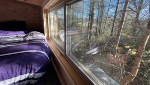 Una habitación de cabaña de madera con una cama, un ventanal y vistas a un bosque.