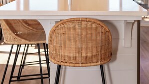 Una cocina con una isla grande, taburetes de bar y una lámpara colgante.