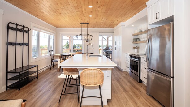Una cocina moderna con una isla central, electrodomésticos de acero inoxidable y techo de madera.