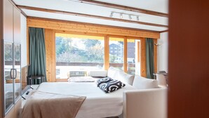 A modern bedroom with a bed, a sofa, a large window, and a view of the outdoors. - Opale 24 by Interhome (Villars)