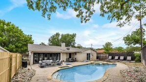 A backyard with a swimming pool, a patio with outdoor furniture, and a house with a covered patio area. - 6 Bed - Swimming Pool - Hot Tub - Prime Location (Irving)