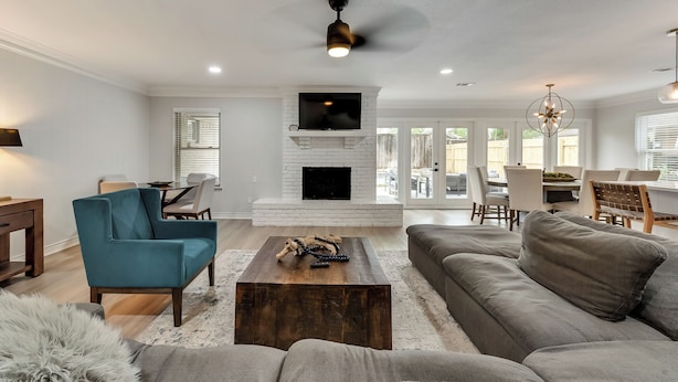 A modern living room with a fireplace, a teal armchair, a gray sofa, and a wooden coffee table. - 6 Bed - Swimming Pool - Hot Tub - Prime Location (Irving)