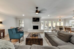 Ein modernes Wohnzimmer mit Kamin, einem blaugrünen Sessel, einem grauen Sofa und einem Holztisch.