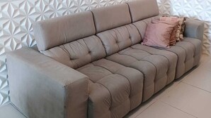Een beige modulaire bank met een geometrisch patroon op de muur erachter.