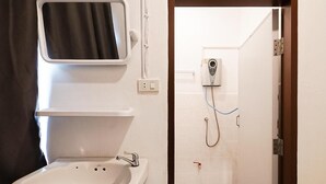 A bathroom with a sink, mirror, and a shower with a handheld showerhead. - GO INN Asiatique (Bangkok)