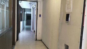 A corridor with a door on the right, a vent on the left, and a sign on the door. - GO INN Asiatique (Bangkok)