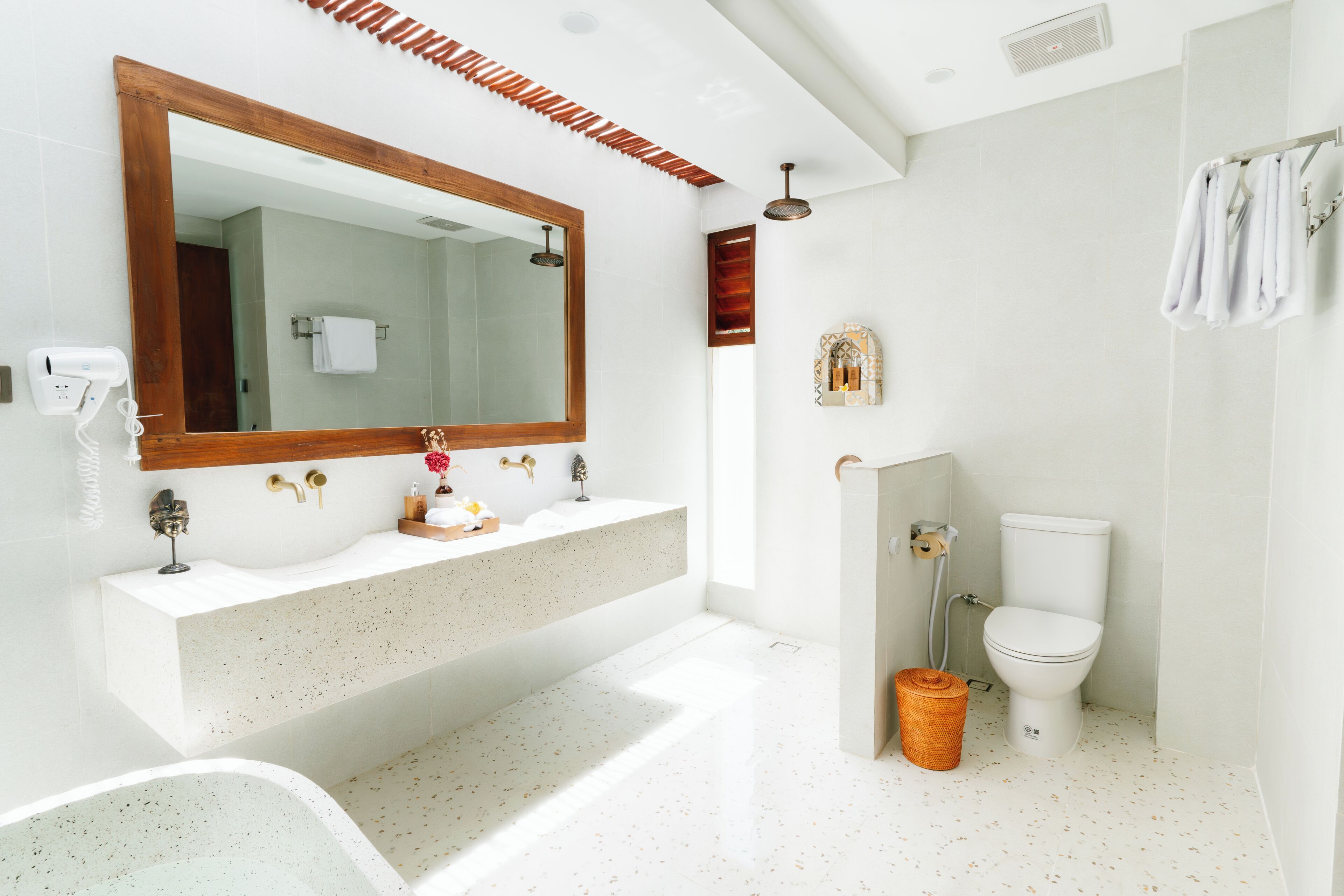 A modern bathroom with a large mirror, two sinks, a toilet, and a shower.
