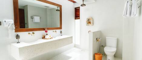 A modern bathroom with a large mirror, two sinks, a toilet, and a shower.