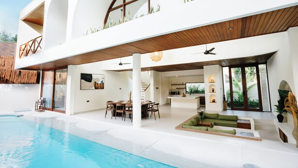 A modern house with a swimming pool, a dining area, and a living room with a sofa and a coffee table. - Luxury Noah Villa (Kuta)