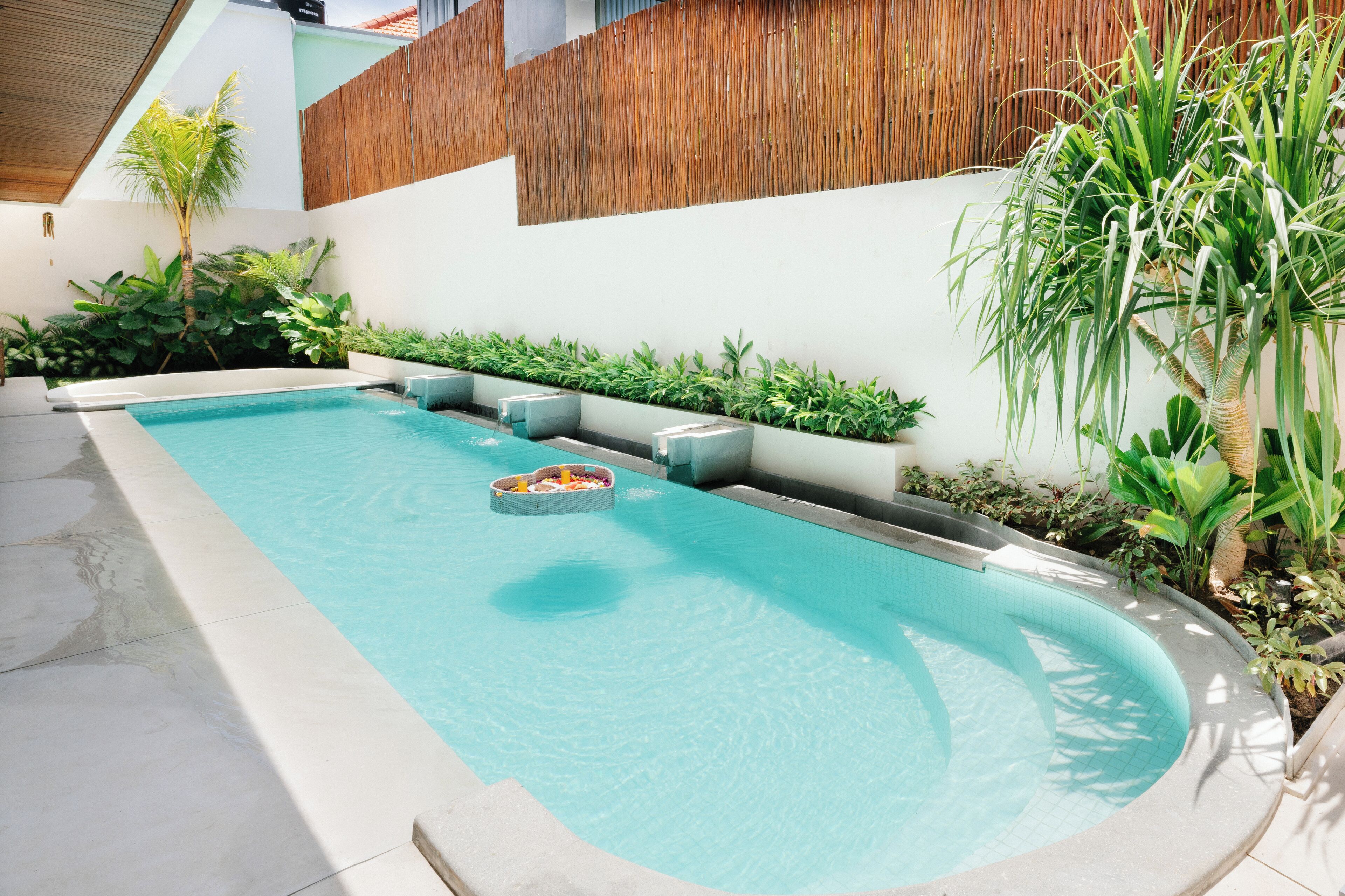 A swimming pool with a built-in seating area and surrounding greenery.