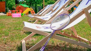Buiten houten lounge stoelen, met een paars badmintonracket erboven.