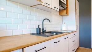 Een moderne keuken met witte kasten, een houten aanrechtblad, een zwarte kraan en een inbouwoven.