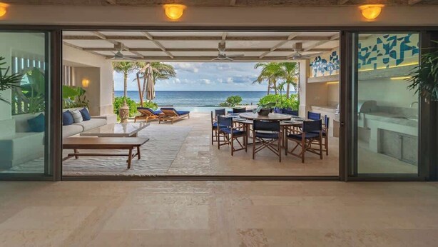A spacious outdoor area with a view of the ocean, furnished with a sofa, chairs, and a dining table.