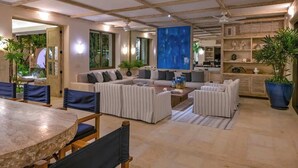 A spacious living area with a large sofa set, a dining table, and a blue abstract painting on the wall.