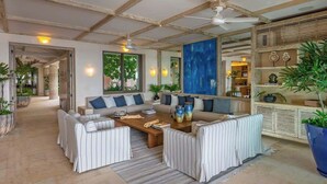 A spacious living area with a high ceiling, a sofa set, a coffee table, and a large blue abstract painting.