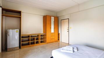 A room with a bed, a wardrobe, a mirror, and a refrigerator.