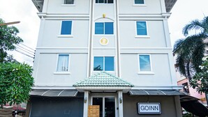 Un immeuble à plusieurs étages, doté d’un toit plat, d’une entrée centrale avec un meuble en bois et d’une enseigne portant l’inscription « GOINN ».