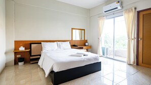 Une chambre d’hôtel comprenant un lit, des tables de chevet, un miroir, un appareil de climatisation, une fenêtre avec des rideaux et une porte.