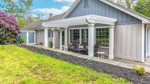 Ein Haus mit überdachter Terrasse, Sitzgelegenheiten im Freien und einem Garten.