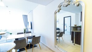 Un espace repas moderne, agrémenté d’un grand miroir, d’une table à manger et de chaises.