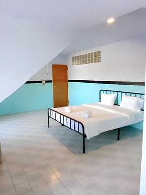 A single bed with a headboard, a wooden door, and a light blue wall with a black stripe. - Mitr inn Phuket Old town (Phuket)