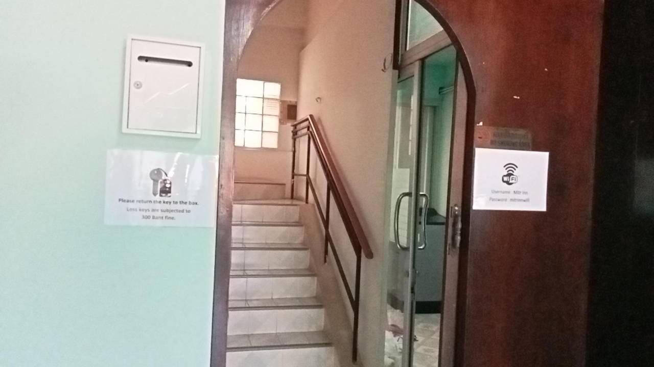 A staircase with a handrail, a door with a Wi-Fi symbol, and a sign instructing to return keys to a box.