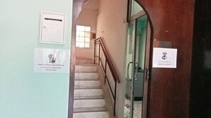 A staircase with a handrail, a door with a Wi-Fi symbol, and a sign instructing to return keys to a box. - Mitr inn Phuket Old town (Phuket)