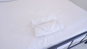 A neatly made bed with white linens and a folded towel on the bed. - Mitr inn Phuket Old town (Phuket)
