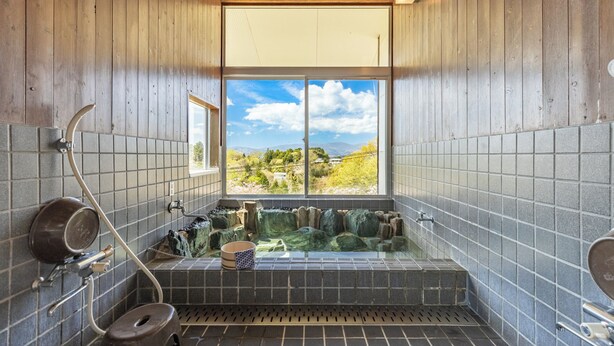 Un baño con vistas a un paisaje montañoso, una bañera y una zona de ducha.