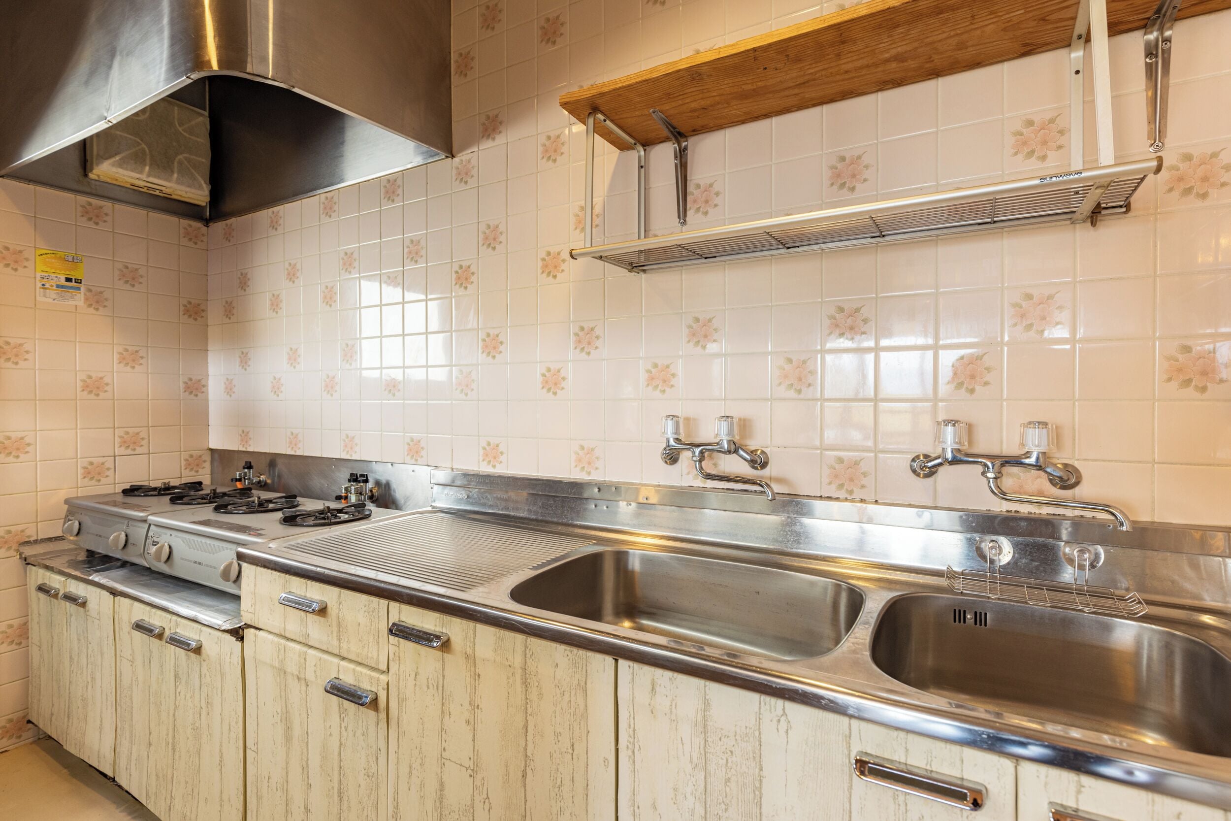 A kitchen with a gas stove, double sink, and wooden cabinets.