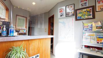 A reception area with a wooden counter, a potted plant, and various items on the counter.