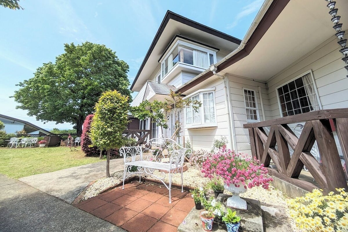 Ein Haus mit einer Veranda, einer Bank und Topfpflanzen.