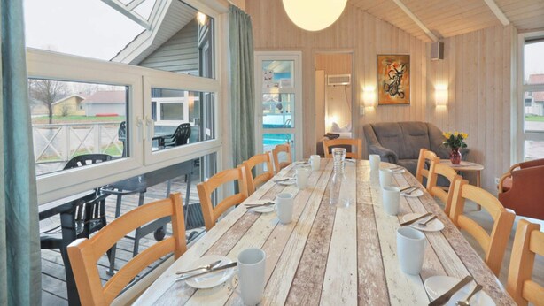 A dining area with a long wooden table, wooden chairs, and a hanging light fixture. - 4 Star Holiday Home in Ottendorf (Otterndorf)