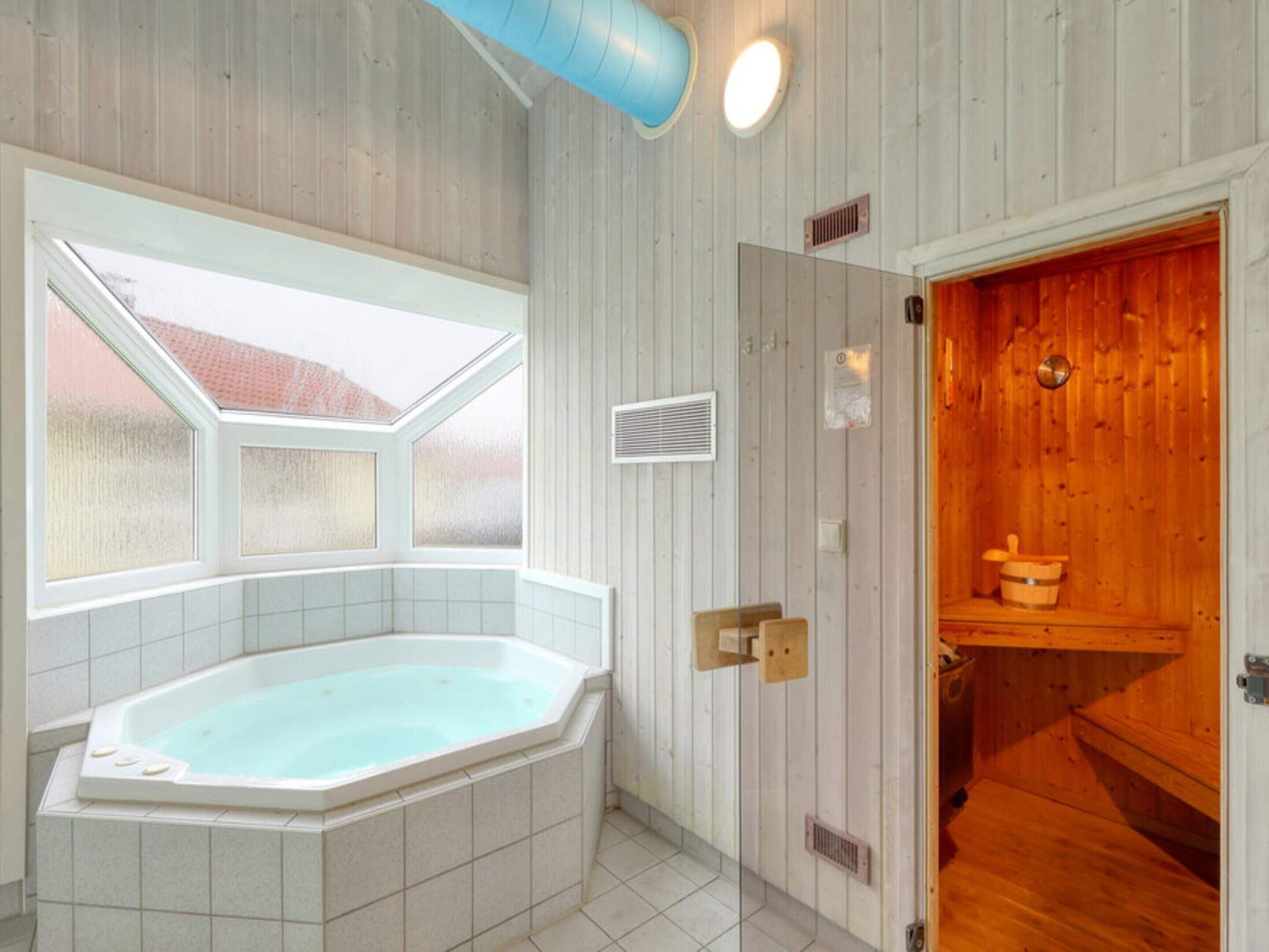 Un baño con una bañera independiente, un tragaluz y una zona de sauna de madera.